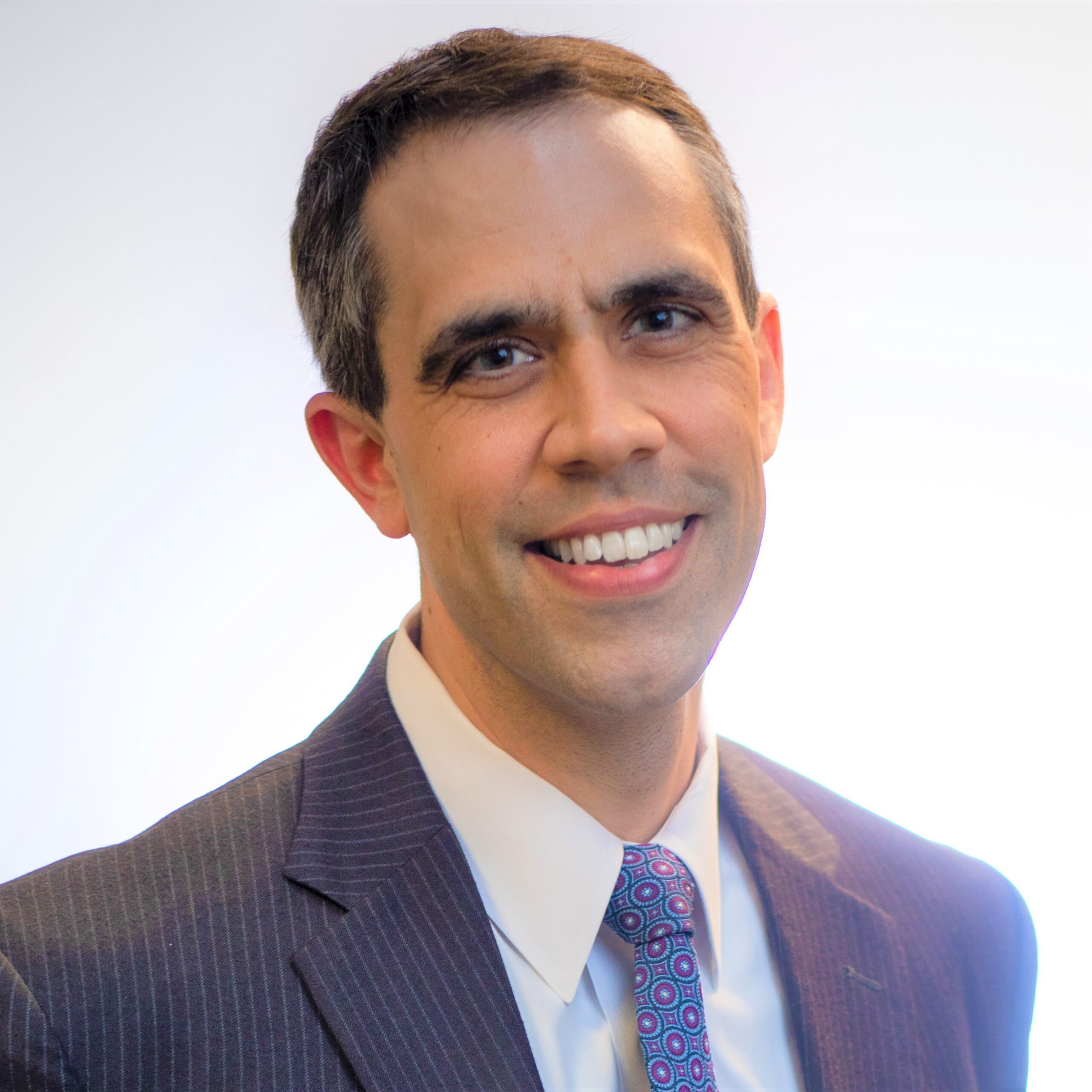 Matt, a white man with brown hair, wears a white shirt, purple tie and black blazer.