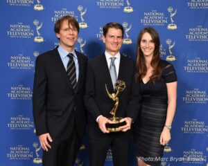 Coleman Cowan stands in the center with co-producers Graham Messick, left, and Eve Salomon, right. Cowan holds the Emmy award. 