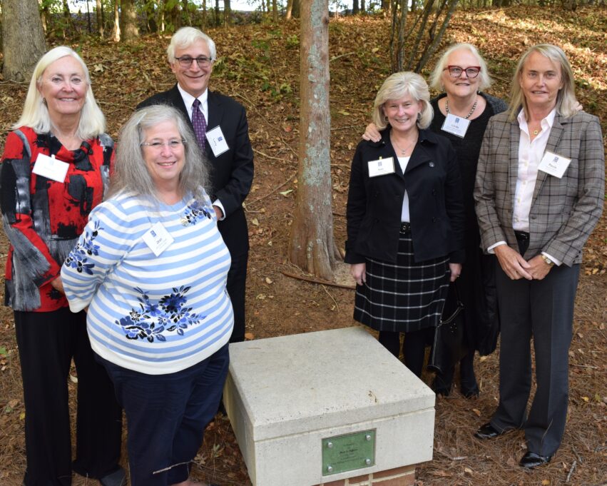 The garden outside the bar center is pictured. Six individuals stand near the bench, with three on each side.