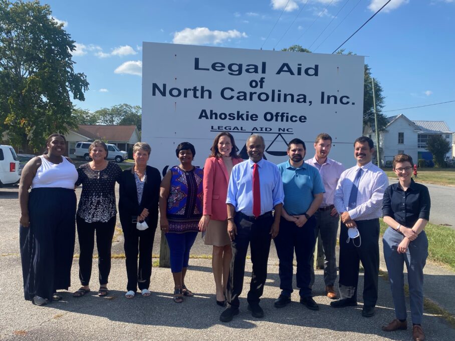 Nine Legal Aid employees from the Ahoskie Office stand outside with Ashley in the center on a bright, sunny day.