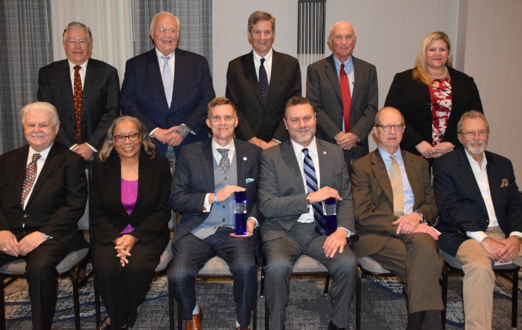 This year's honorees sit in the center of the lower row and nine previous recipients sit and stand around them.