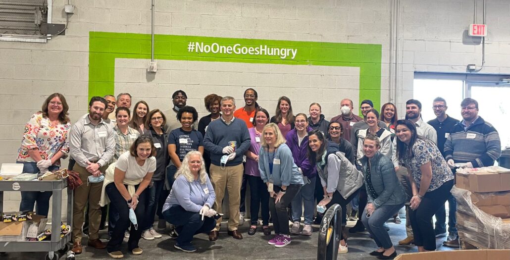 A group of individuals is pictured with a sign on the wall that reads, "#noonegoeshungry." Attorney General Josh Stein is pictured in the center of the group.