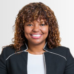 Gwendolyn, a Black woman with curly brown hair, wears a white blouse and black jacket with white piping. 