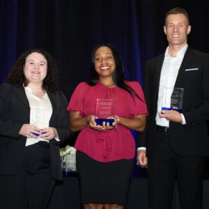 Meghan Moran is a woman with brown hair wearing a white blouse and black suit, Lakethia Jefferies is a Black woman with black hair wearing a red blouse and black skirt, and D.J. Dore is a white man wearing a white shirt and black suit.