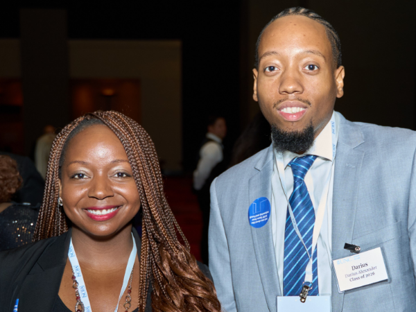 April Franklin, a Black woman with long brown hair, wears a black blouse and blazer, and Darius Alexander, a Black man with black hair and a black beard, wears a white shirt, blue tie and grey jacket.