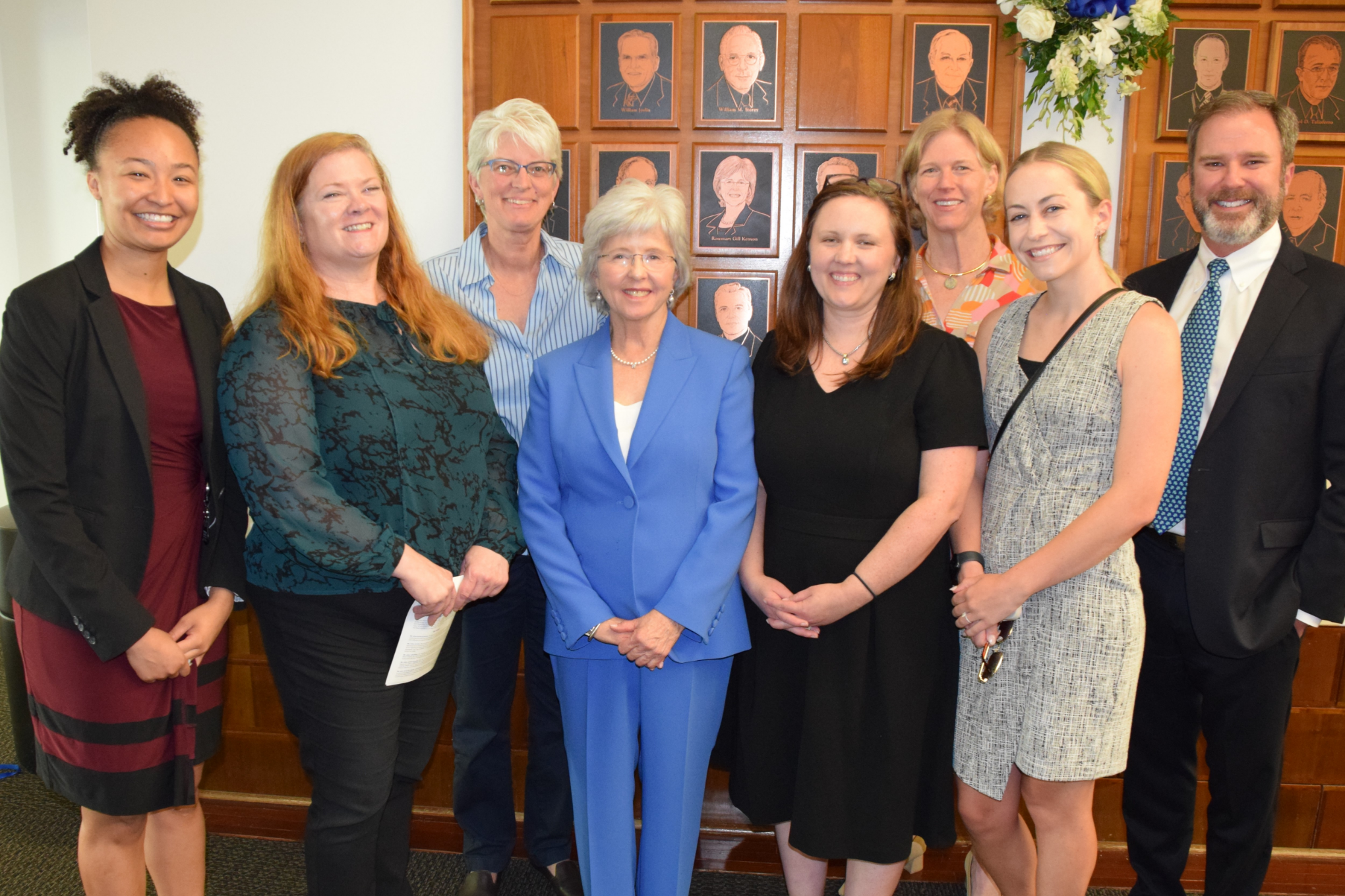 Eight attorneys are pictured in professional attire and they are smiling.