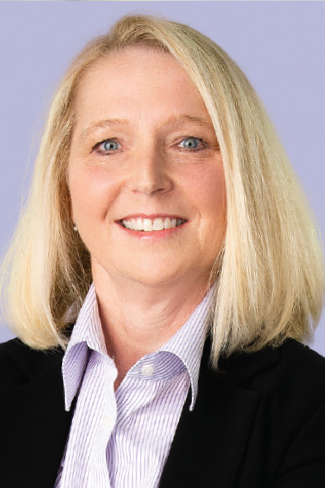 Tammy Stringer is a white woman with blond hair. She is wearing a white and purple striped blouse with a black blazer.