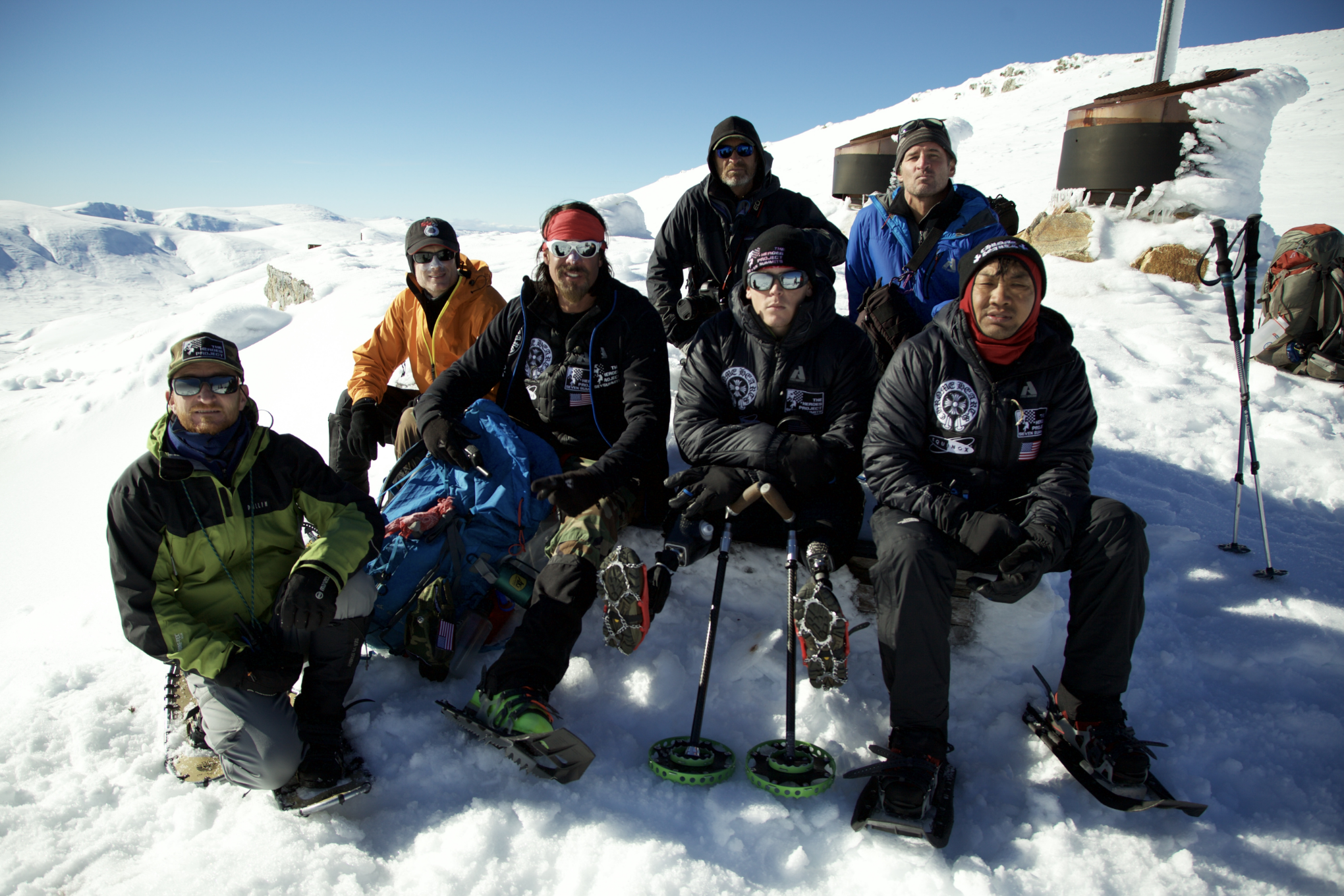 Cowan is pictured with Medvetz, Blunt and the crew. Cowan wears an orange ski jacket with a hat and black pants, Medvetz wears a red bandana, black jacket and pants, and Medvetz wears a black hat, black jacket and sunglasses.